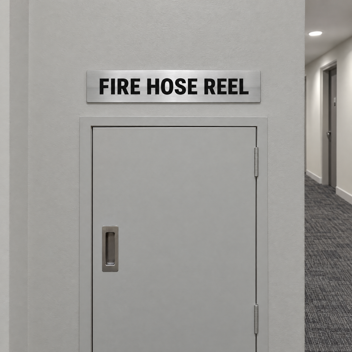 Brushed silver and black Fire Hose Reel sign above a fire hose reel cabinet in an Australian building
