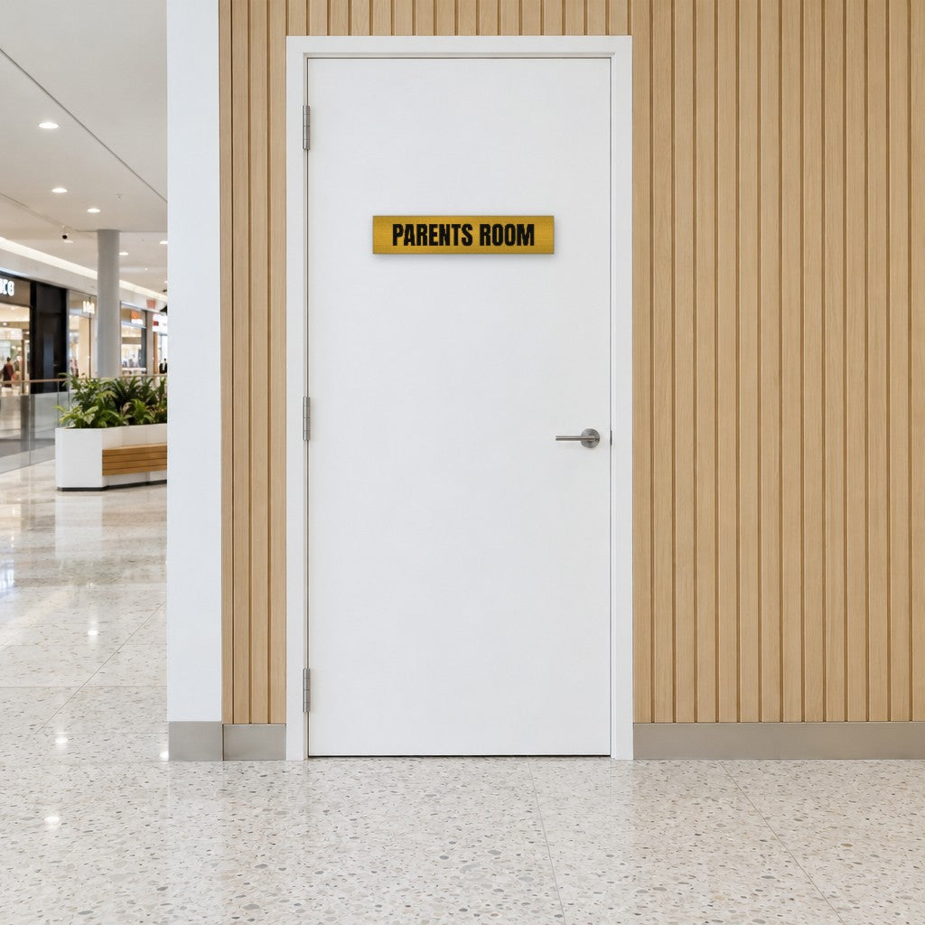 Brushed gold and black Parents Room sign on a parents room door in an Australian shopping centre