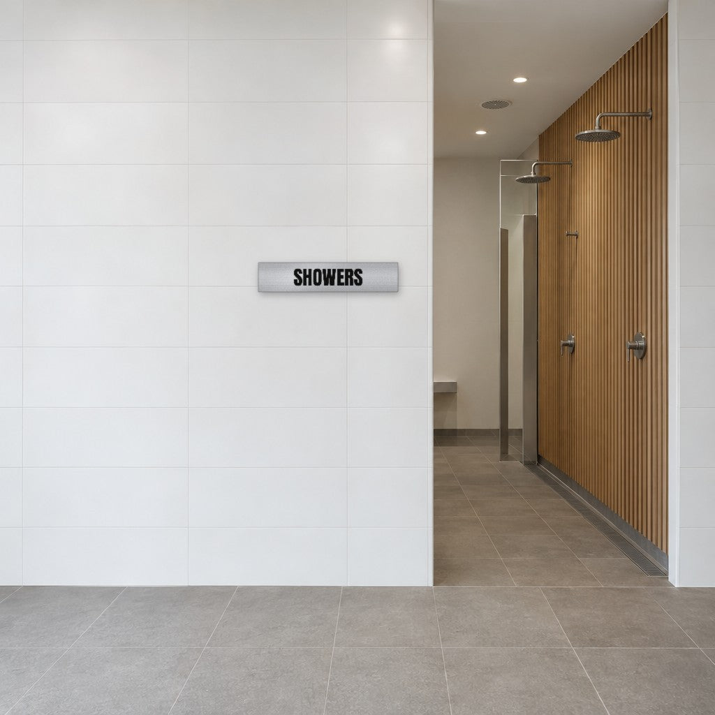 Brushed silver and black Showers sign on the tiled wall beside the showers in an Australian end-of-trip facility