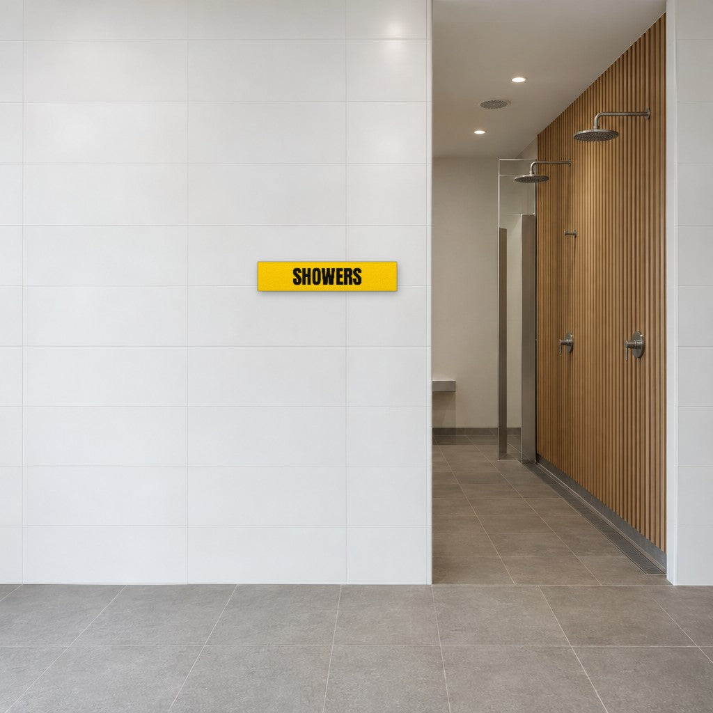 Yellow and black Showers sign on the tiled wall beside the showers in an Australian end-of-trip facility