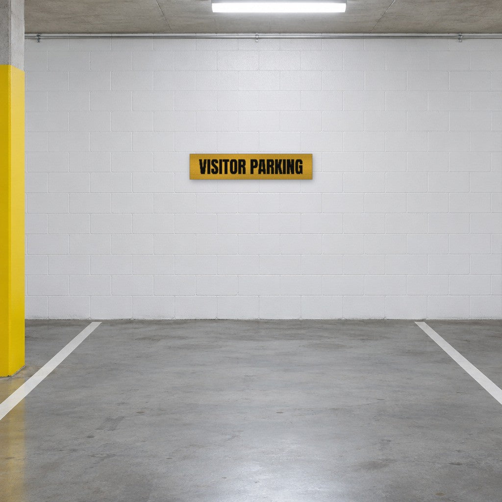 Brushed gold and black Visitor Parking sign on the wall of a visitor parking bay in an Australian basement car park