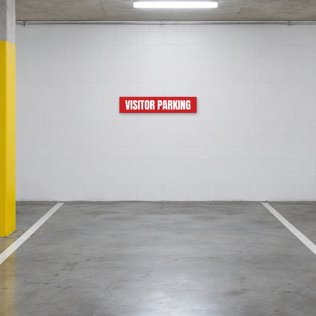 Red and white Visitor Parking sign on the wall of a visitor parking bay in an Australian basement car park