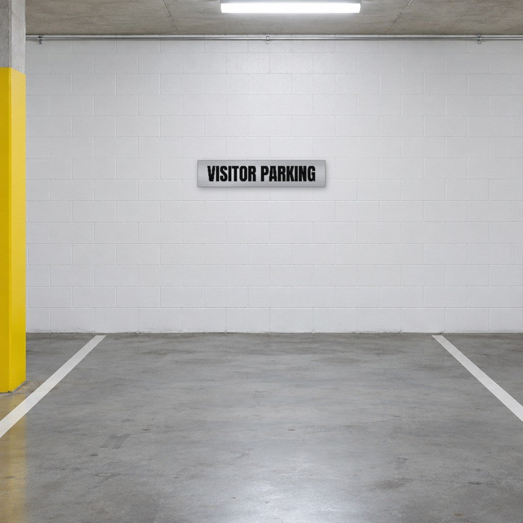 Brushed silver and black Visitor Parking sign on the wall of a visitor parking bay in an Australian basement car park