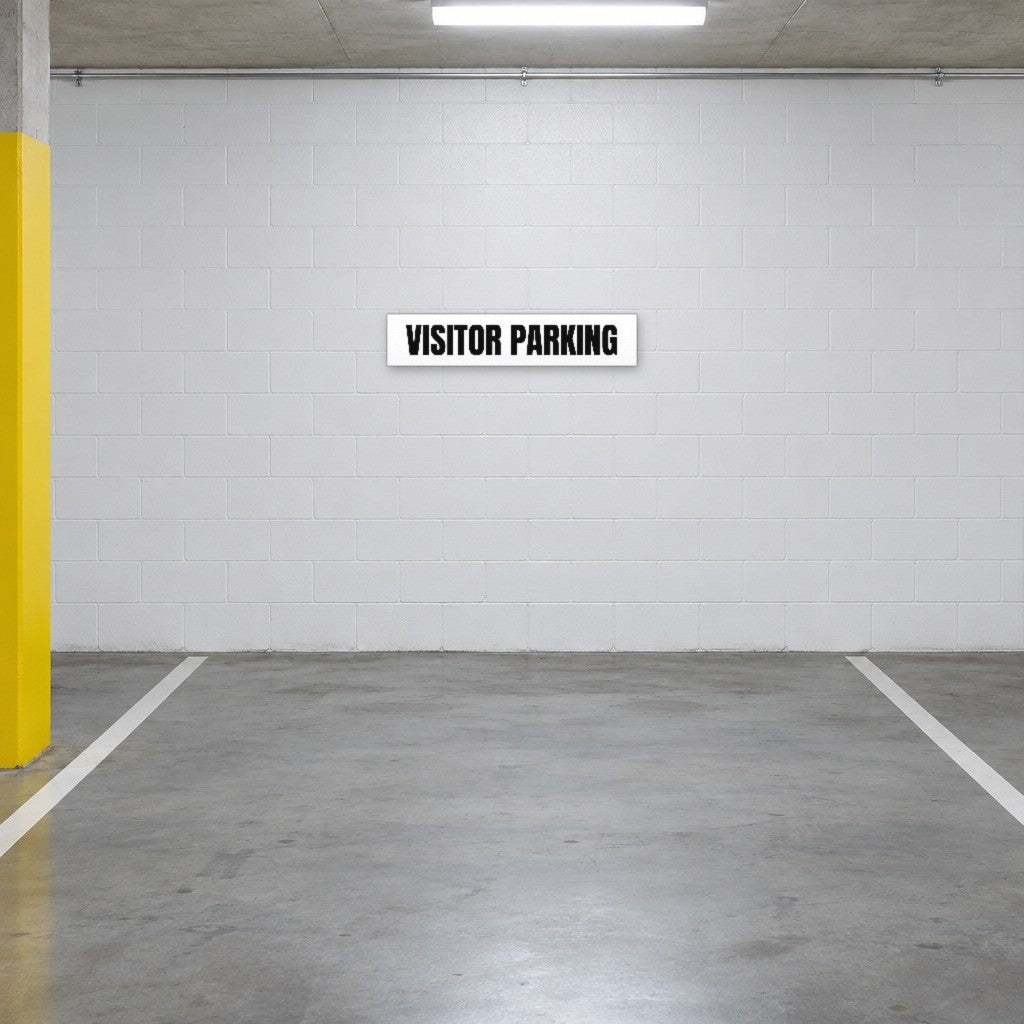 White and black Visitor Parking sign on the wall of a visitor parking bay in an Australian basement car park